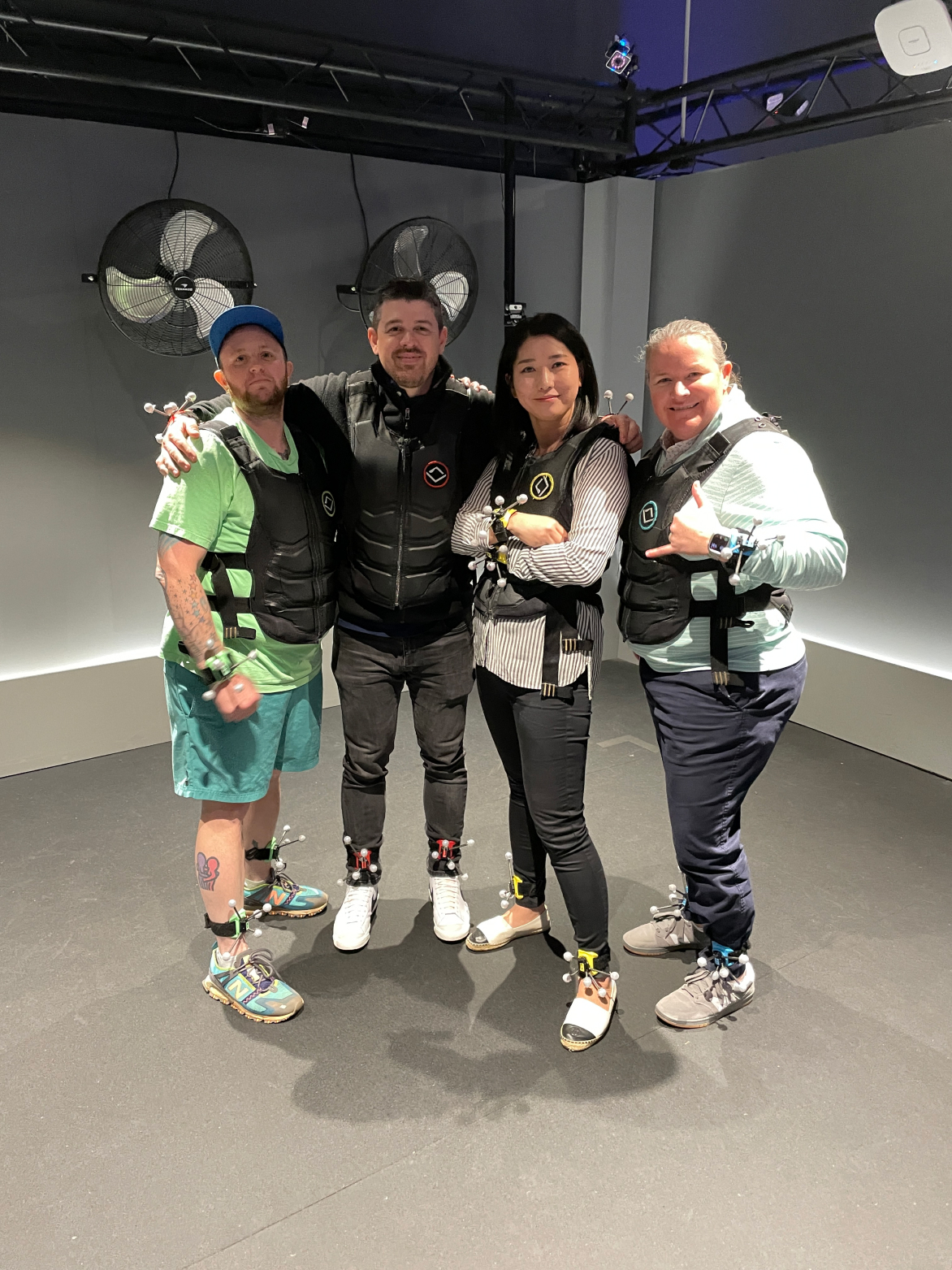 Four people wearing motion capture suits at a team-building event, showcasing company culture and teamwork.