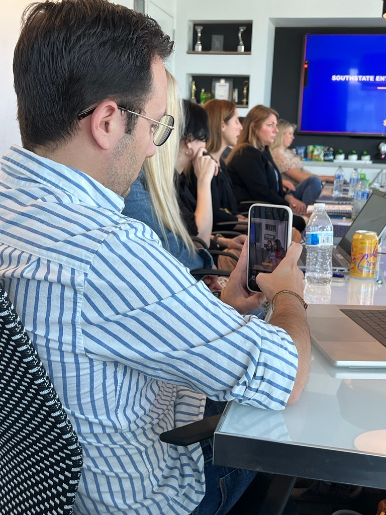 People seated around a conference table during a SouthState Bank QBR meeting, with one person in the foreground taking a photo with their phone.