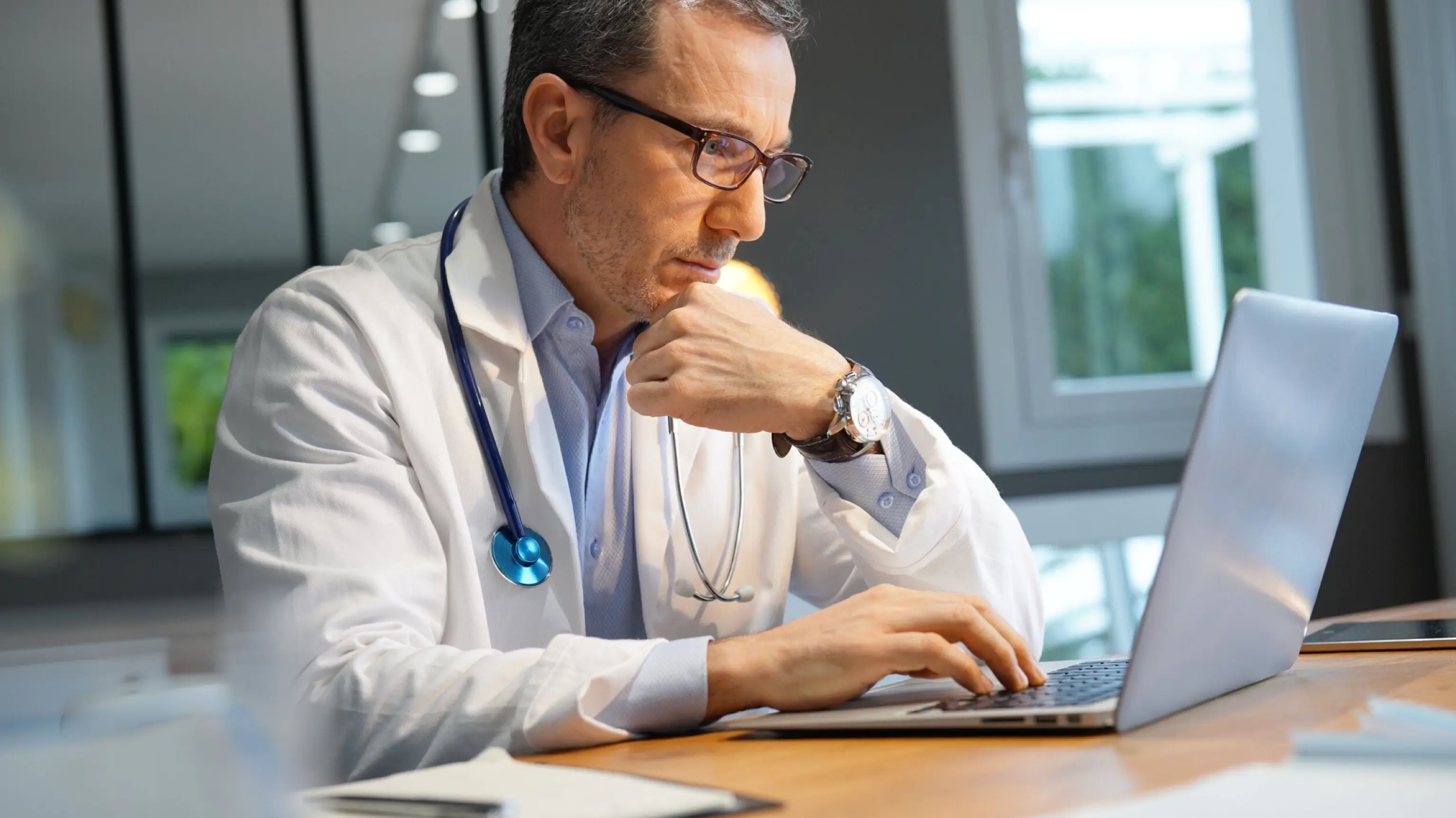 Doctor working on revenue cycle management for hospital on laptop