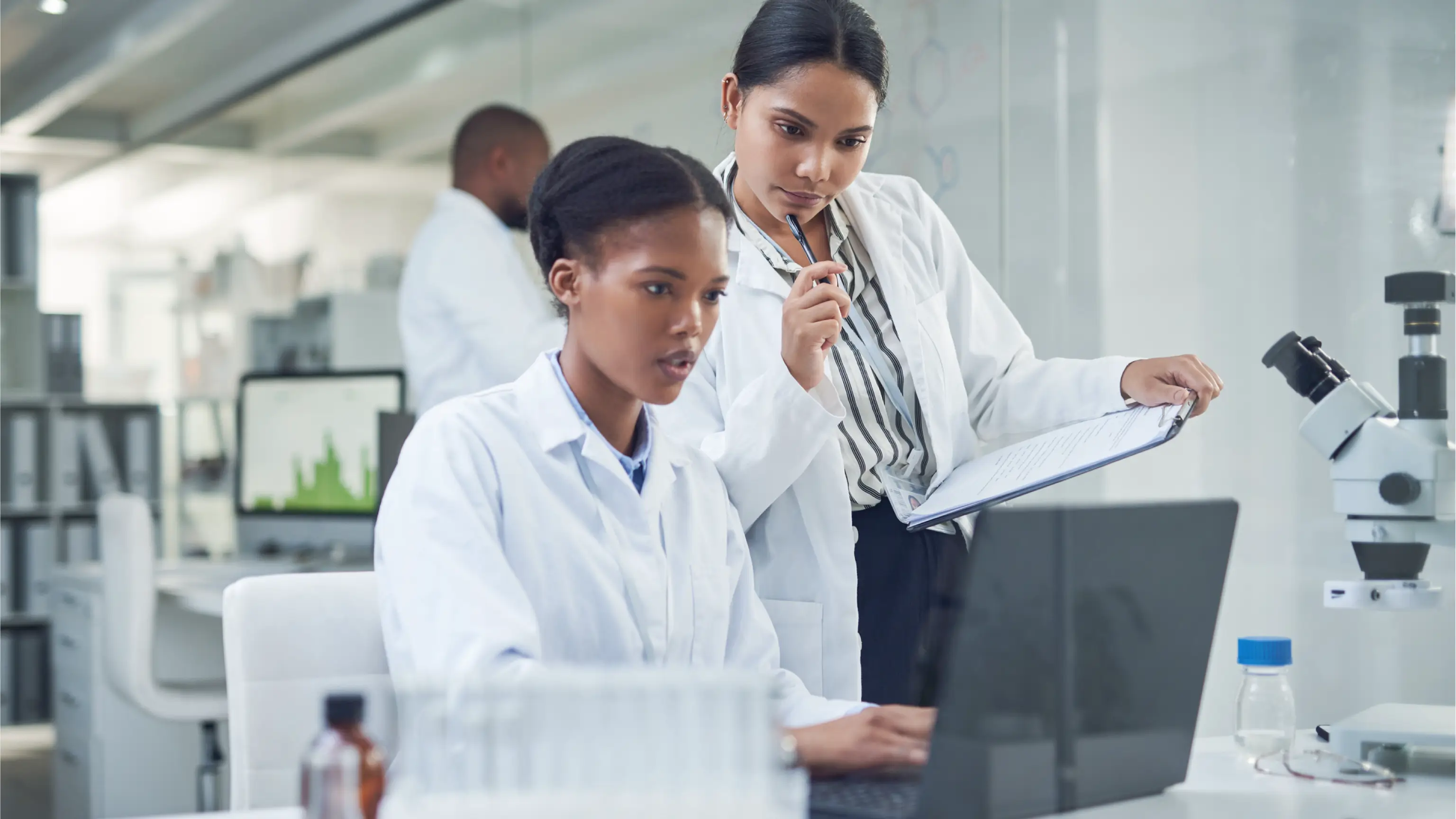 Two female lab technicians discussing blood sample at hospital