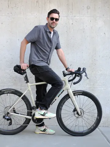 Clint Keener, Art Director at Sagepath, leaning on bicycle in front of wall